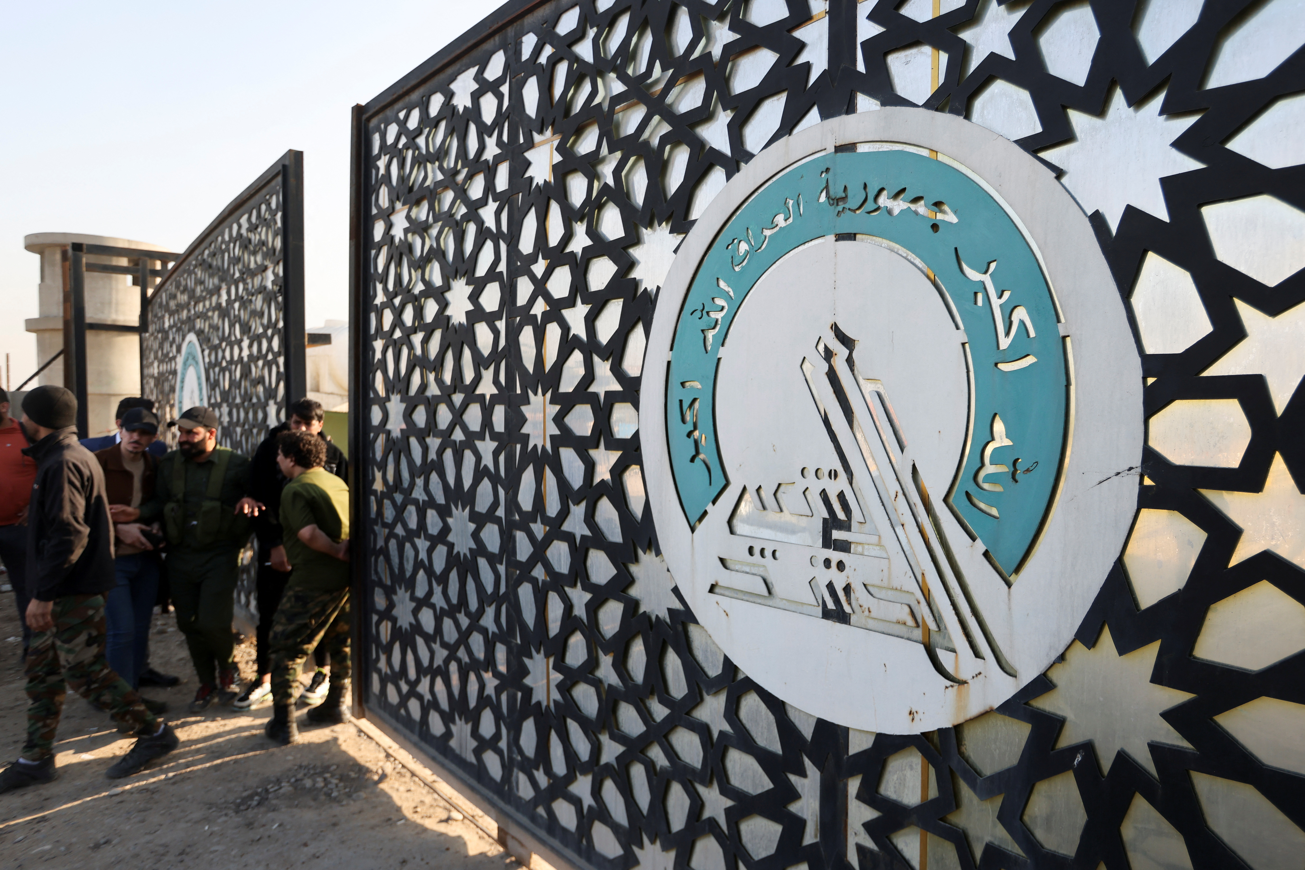 Members of an Iraqi Shi'ite armed group stand guard after an attack by a drone strike on an Iran-backed militia headquarters in Baghdad