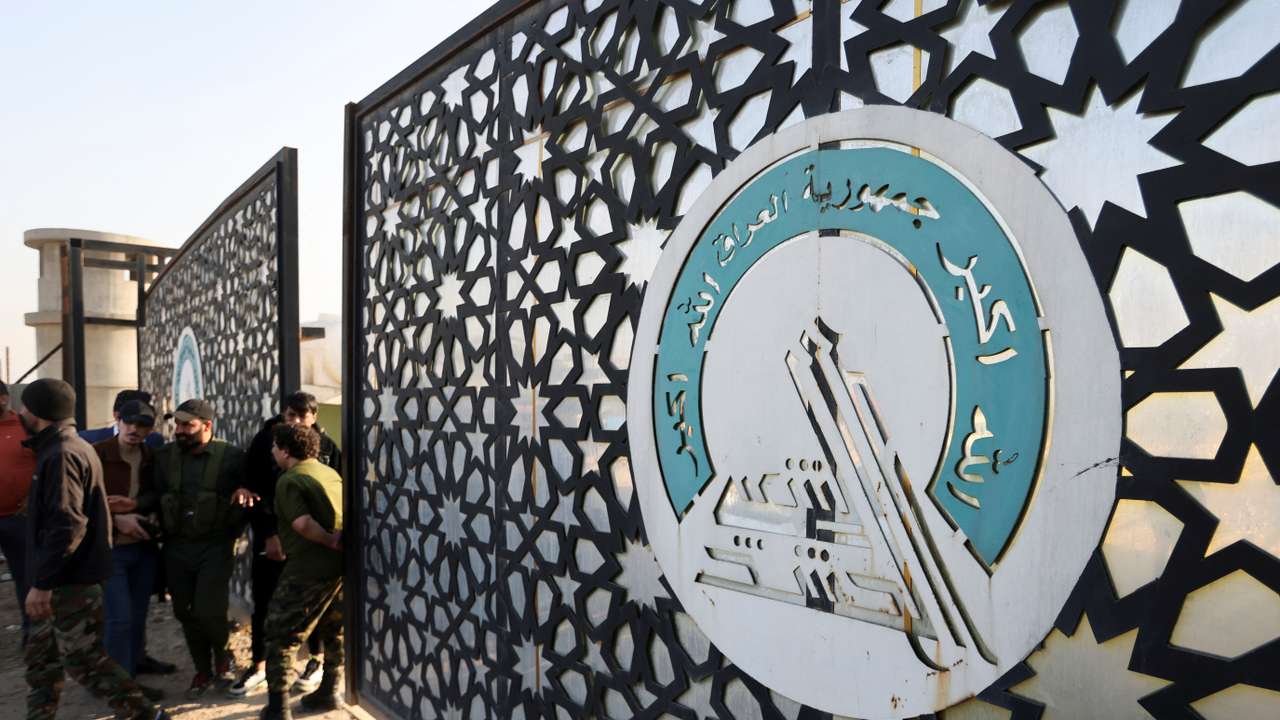 Members of an Iraqi Shi'ite armed group stand guard after an attack by a drone strike on an Iran-backed militia headquarters in Baghdad