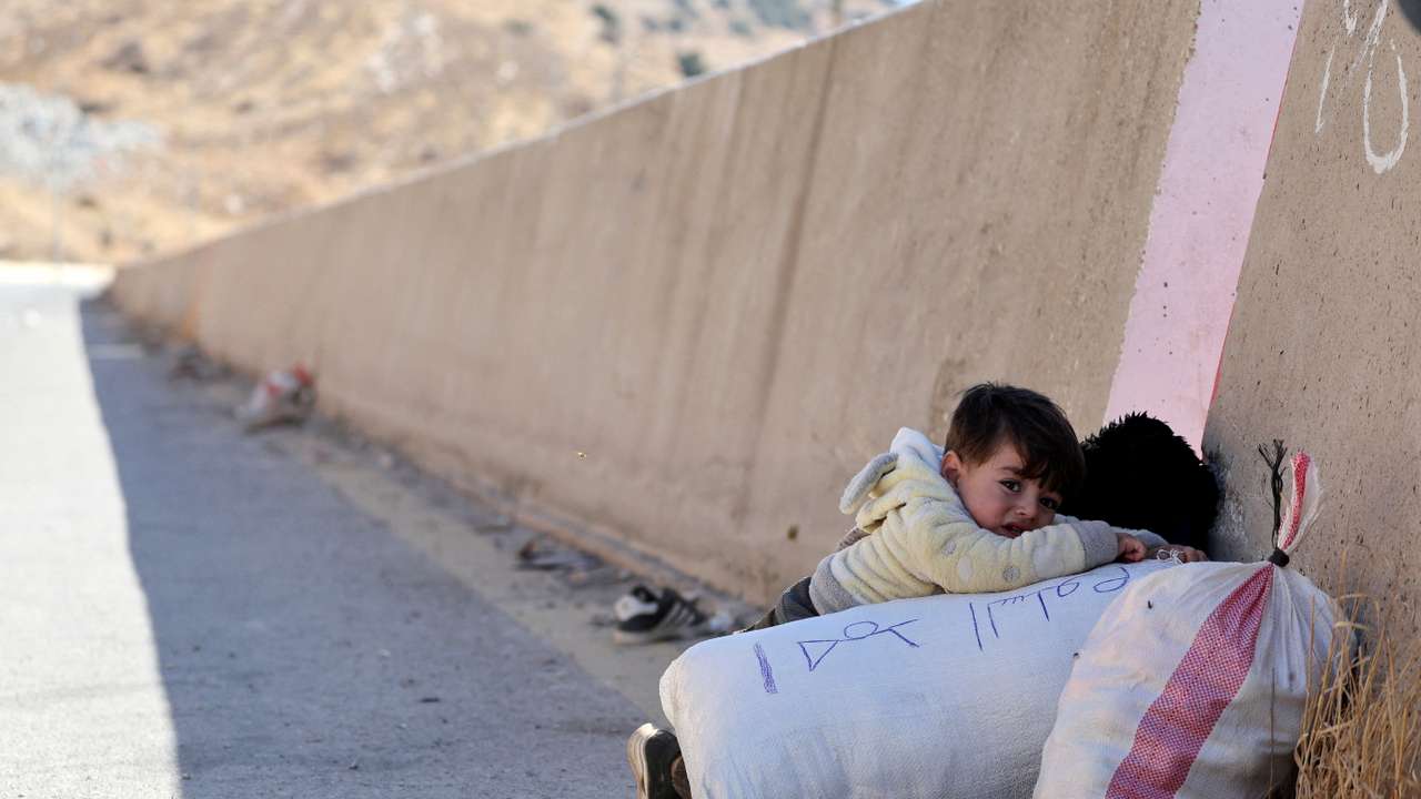 A child holds onto their belongings while crossing from Lebanon into Syria, as people flee the ongoing hostilities between Hezbollah and Israeli forces, at Masnaa border crossing