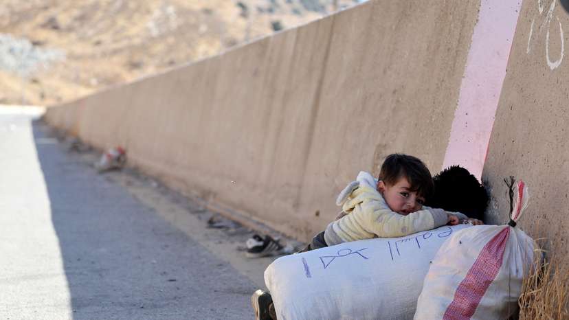 A child holds onto their belongings while crossing from Lebanon into Syria, as people flee the ongoing hostilities between Hezbollah and Israeli forces, at Masnaa border crossing