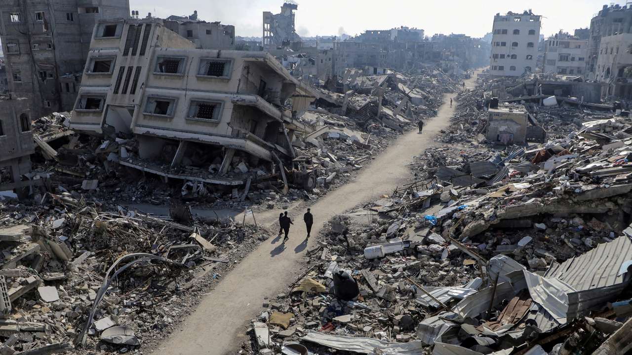 FILE PHOTO: Palestinians walk past destroyed houses, in Jabalia refugee camp