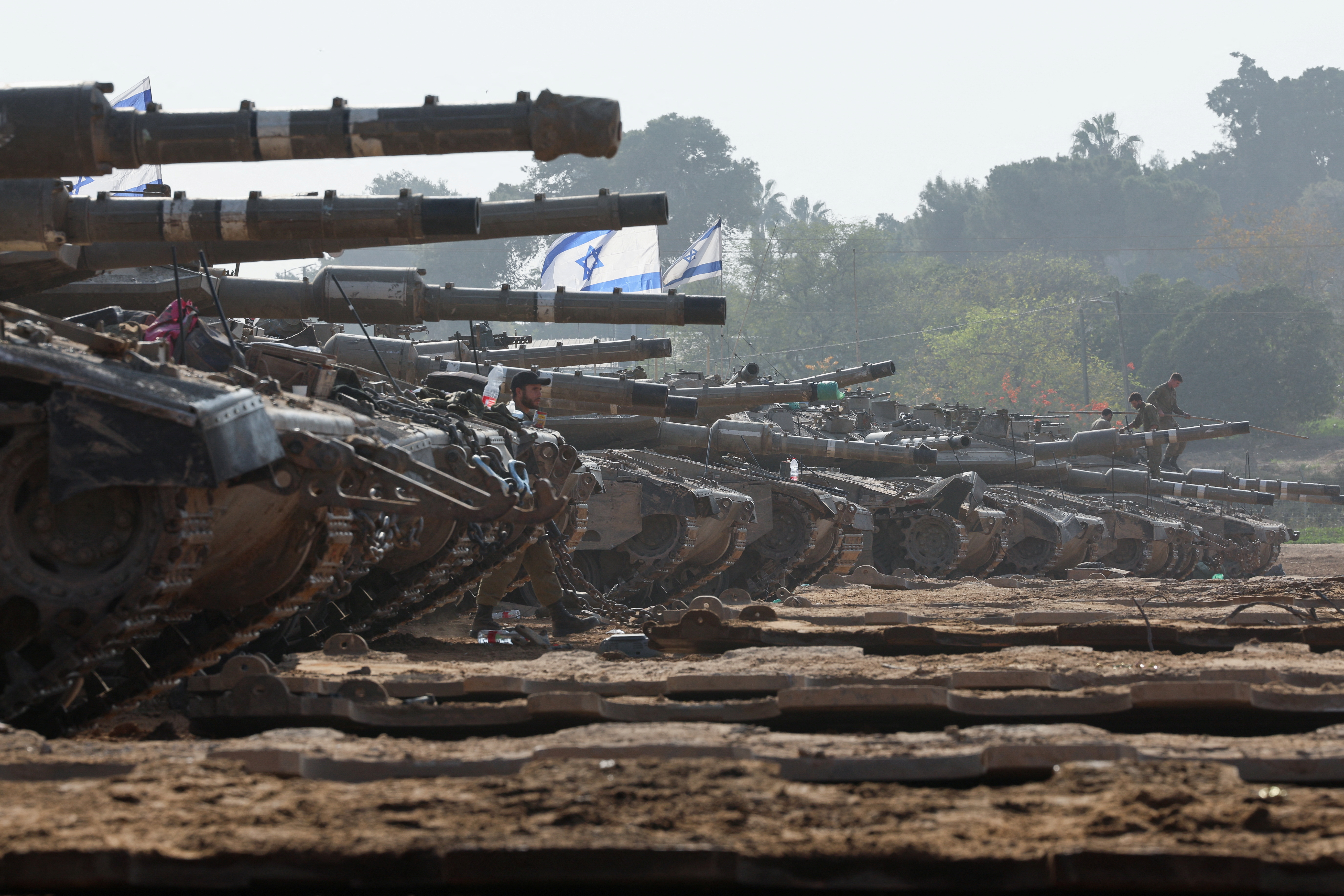 An Israeli soldier walks by tanks, near the Israel-Gaza border