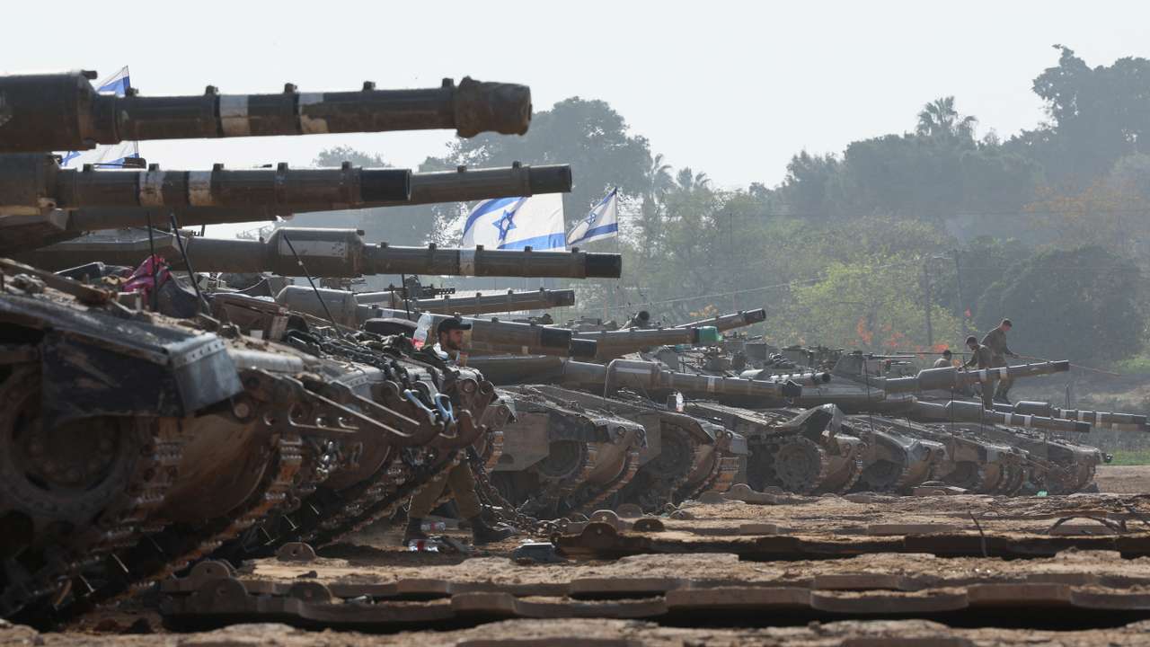 An Israeli soldier walks by tanks, near the Israel-Gaza border