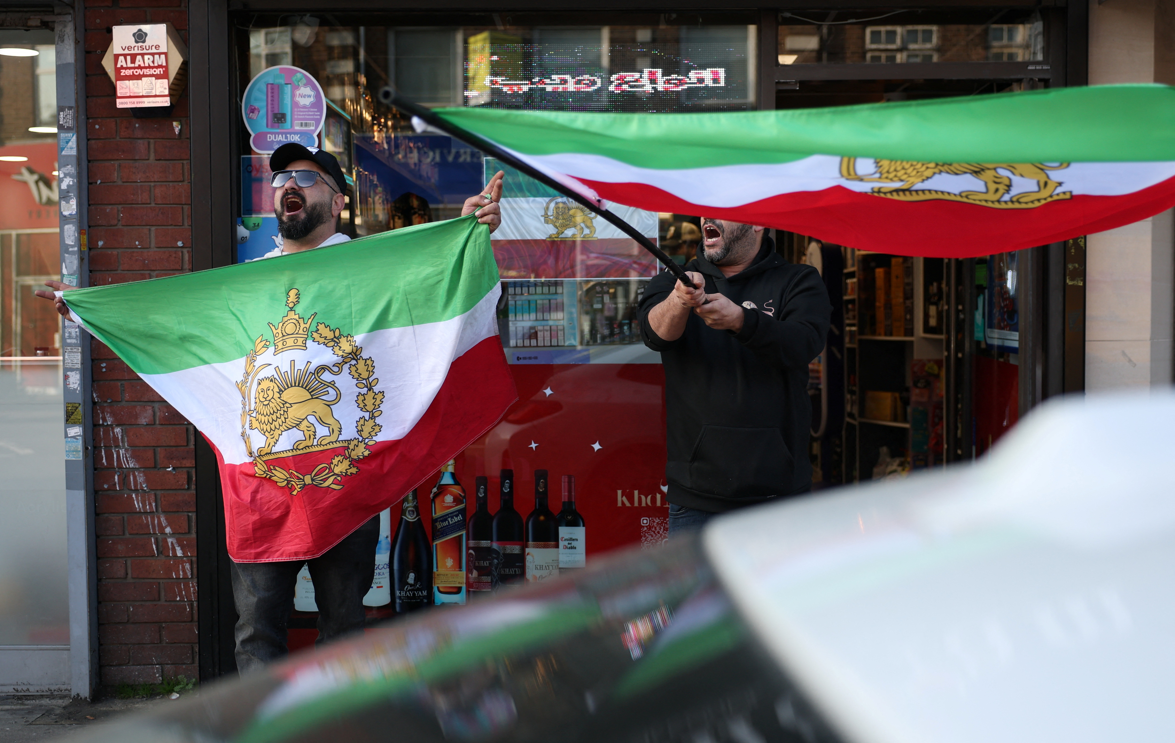 Iranian men shout and hold pre-Iranian Revolution "Lion and Sun" flags in Finchley, London