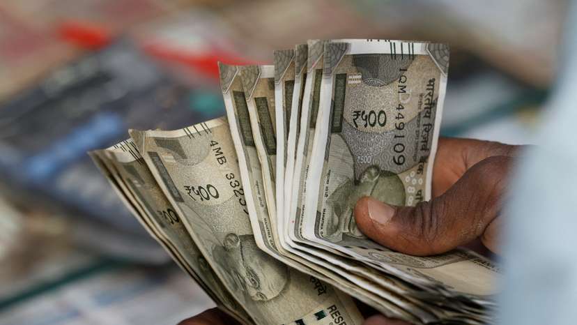 A roadside currency exchange vendor counts notes in New Delhi