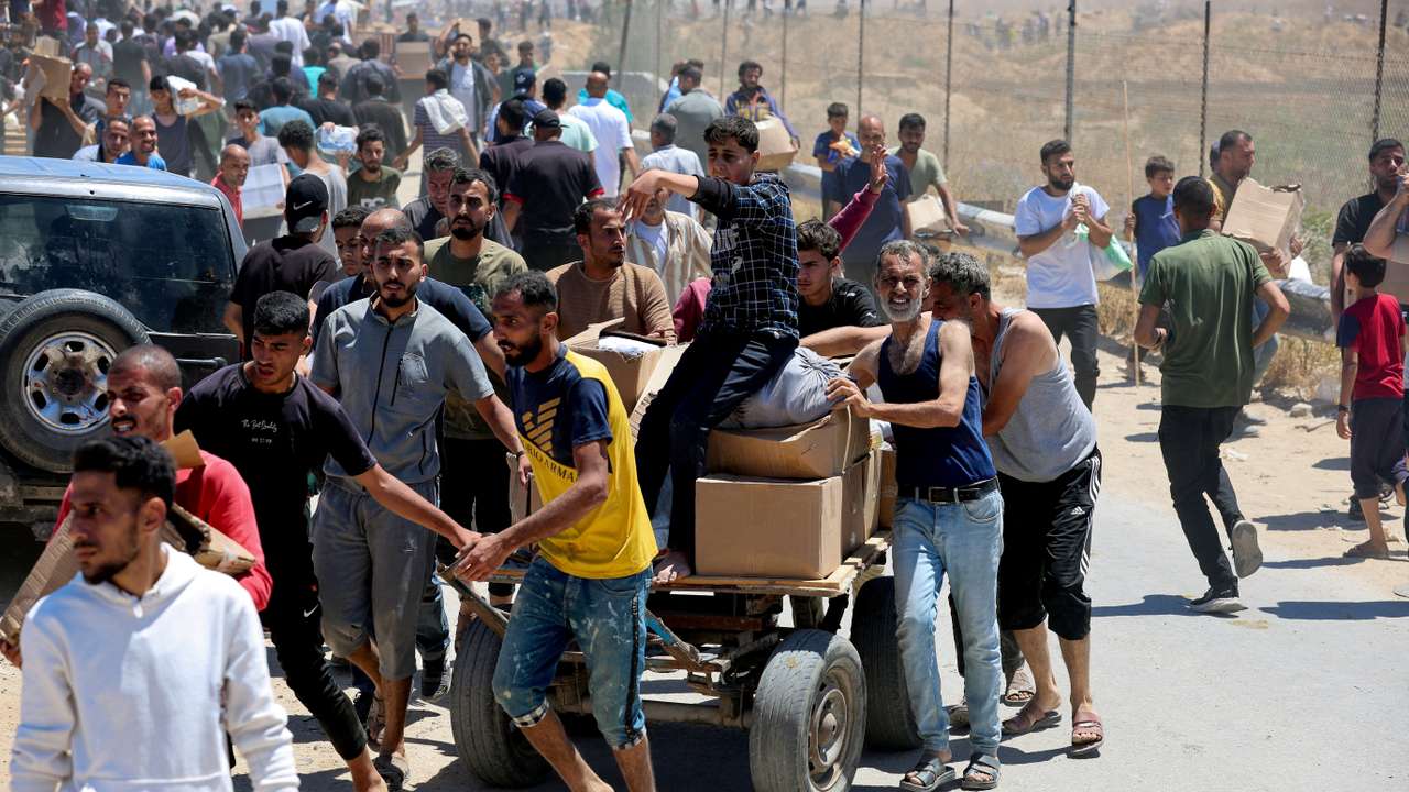 Palestinians walk with aid supplies which they received from the U.S.-backed Gaza Humanitarian Foundation