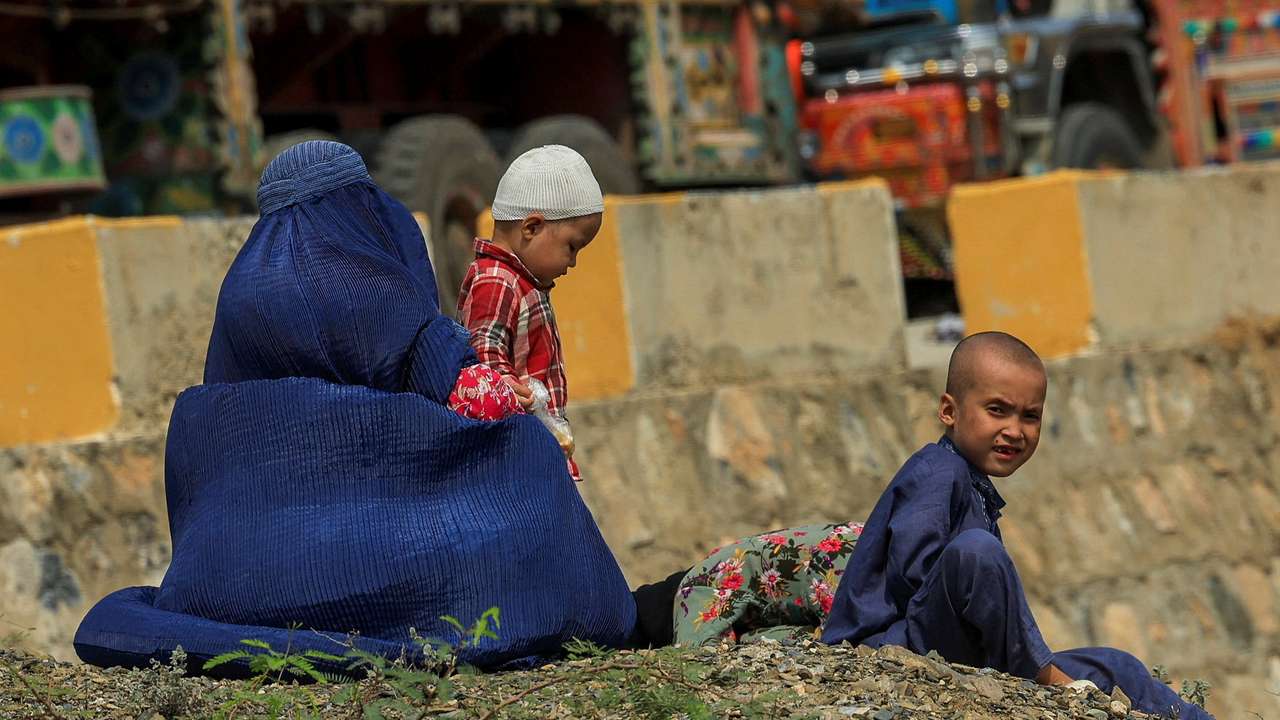 An Afghan family rests, as they head back to Afghanistan after Pakistan started to deport documented Afghan refugees, near Torkham border crossing