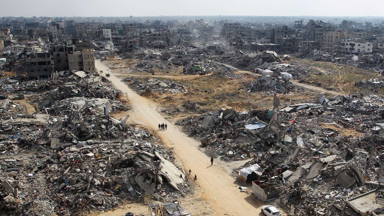 Palestinians walk past the rubble of buildings destroyed during the Israeli offensive in Rafah