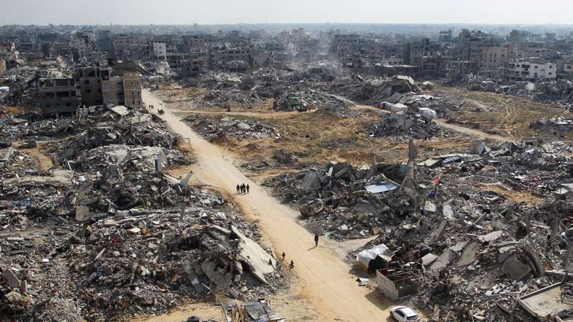 Palestinians walk past the rubble of buildings destroyed during the Israeli offensive in Rafah