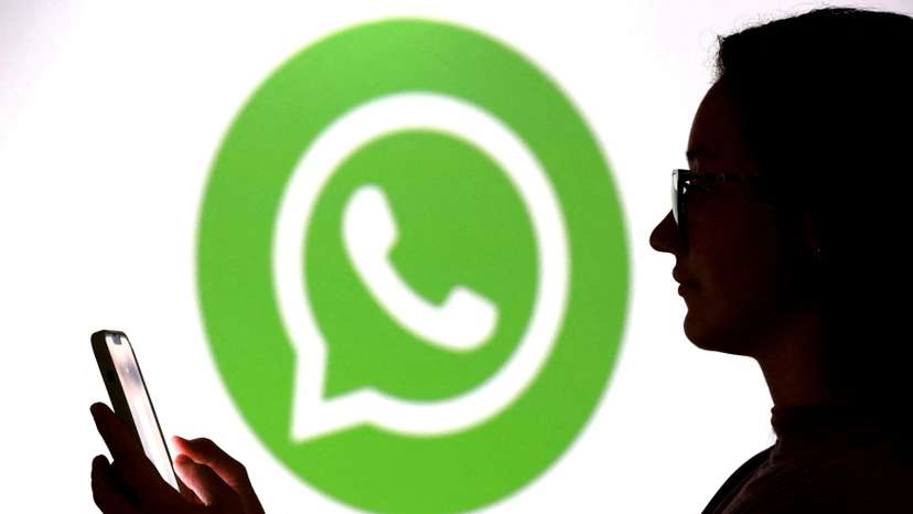 FILE PHOTO: Illustration shows a teenager posing for a photo while holding a smartphone in front of a Whatsapp logo
