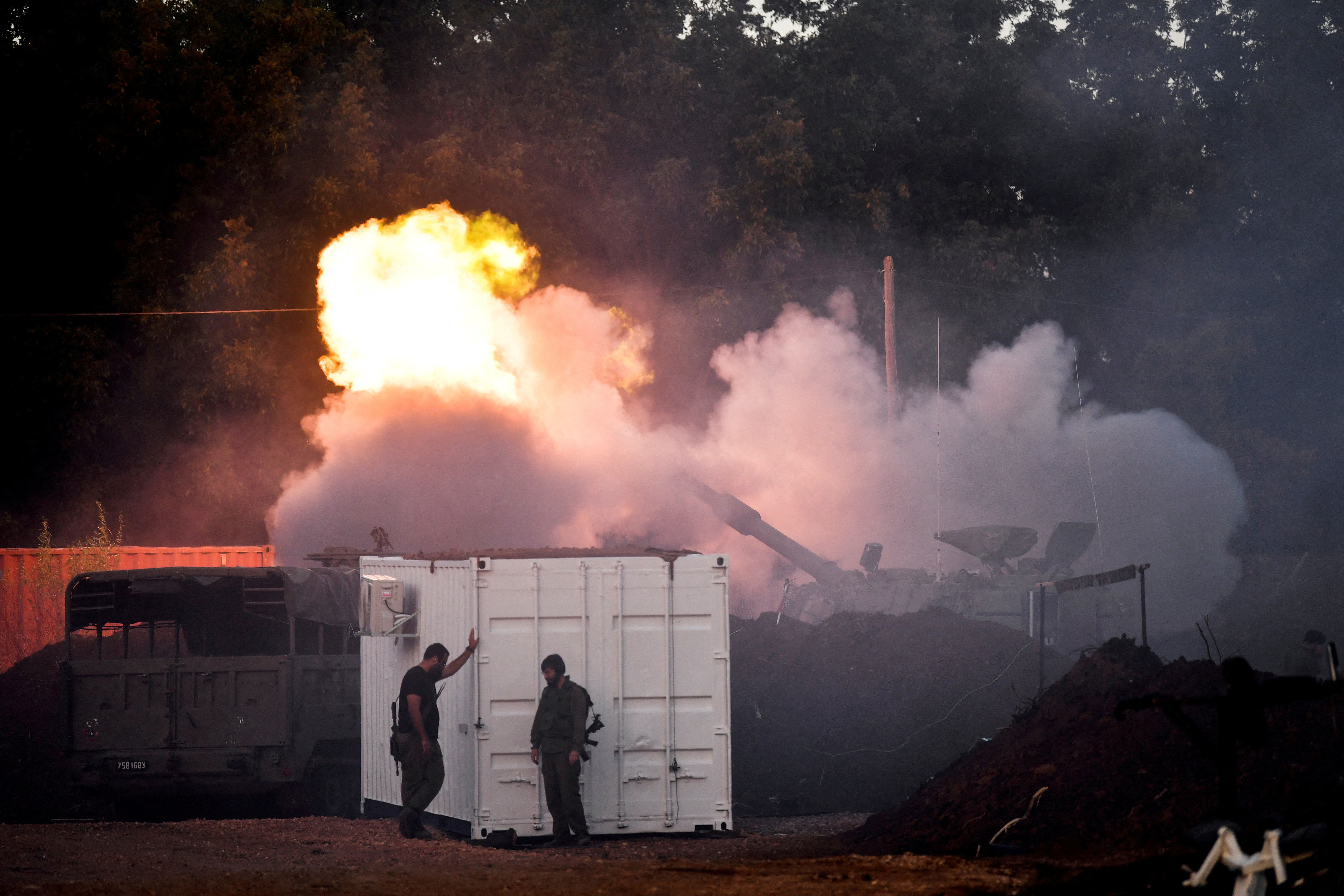 FILE PHOTO: Israeli soldiers stand by, as a mobile artillery unit fires on the Israeli side of the Israel-Lebanon  border