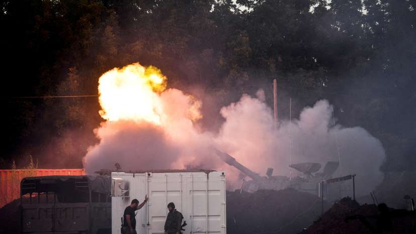 FILE PHOTO: Israeli soldiers stand by, as a mobile artillery unit fires on the Israeli side of the Israel-Lebanon border