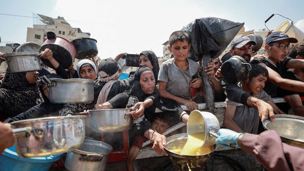 Palestinians wait to receive food from a charity kitchen, in Gaza City