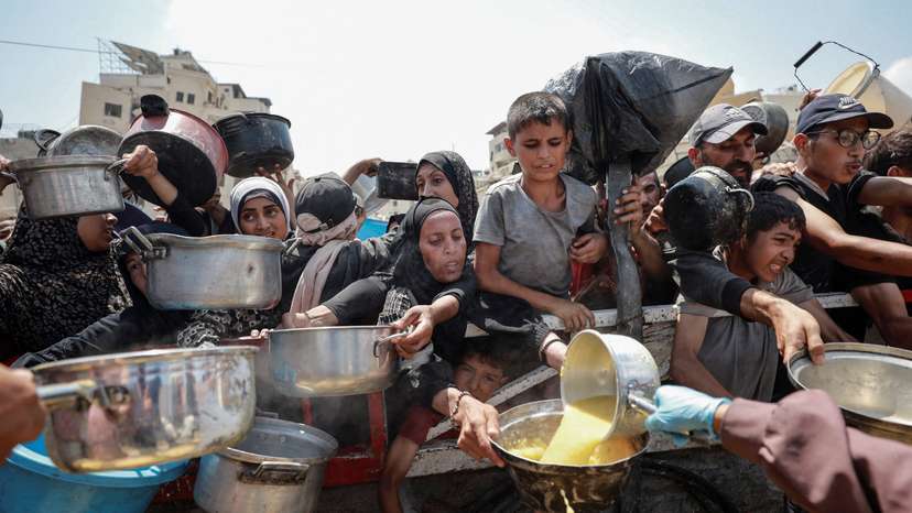 Palestinians wait to receive food from a charity kitchen, in Gaza City
