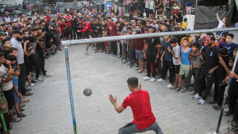 A displaced Palestinian shoots a penalty kick during a soccer match at an UNRWA shelter school, amid Israel-Hamas conflict, in Jabalia in the northern Gaza Strip