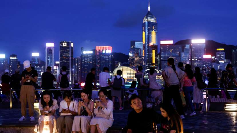 FILE PHOTO: Tourists relax on the waterfront in front of Victoria Harbour, in Hong Kong