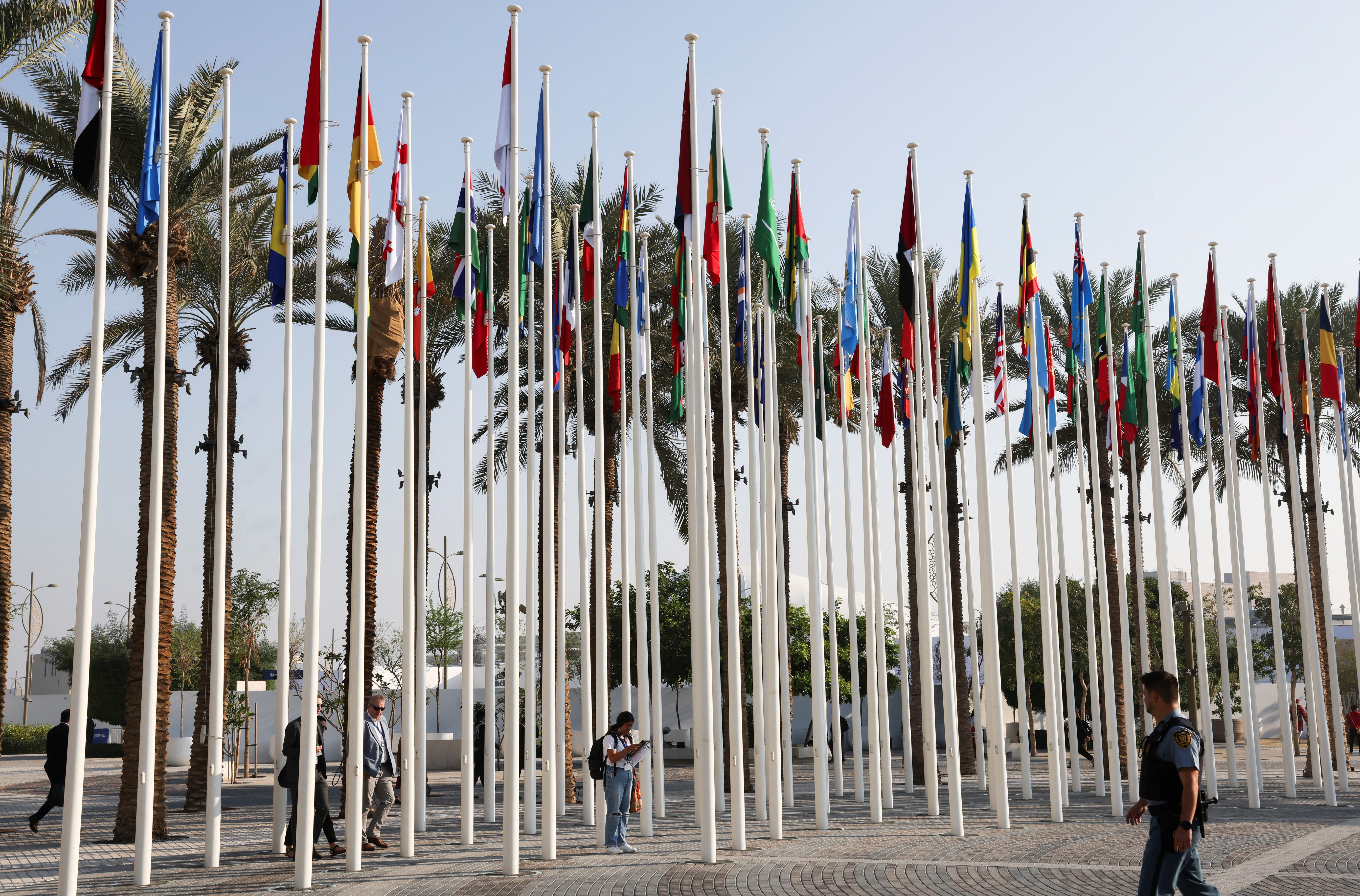 UN security officer walks near the flags at Dubai's Expo City during the United Nations Climate Change Conference (COP28) in Dubai