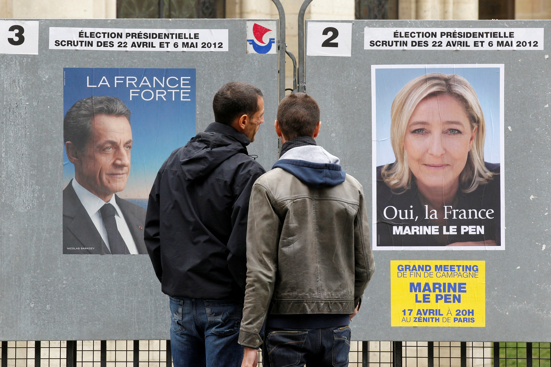 FILE PHOTO: People stop to read the official campaign posters for candidates in the French presidential election in Paris