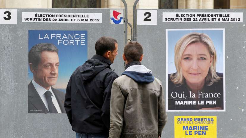 FILE PHOTO: People stop to read the official campaign posters for candidates in the French presidential election in Paris