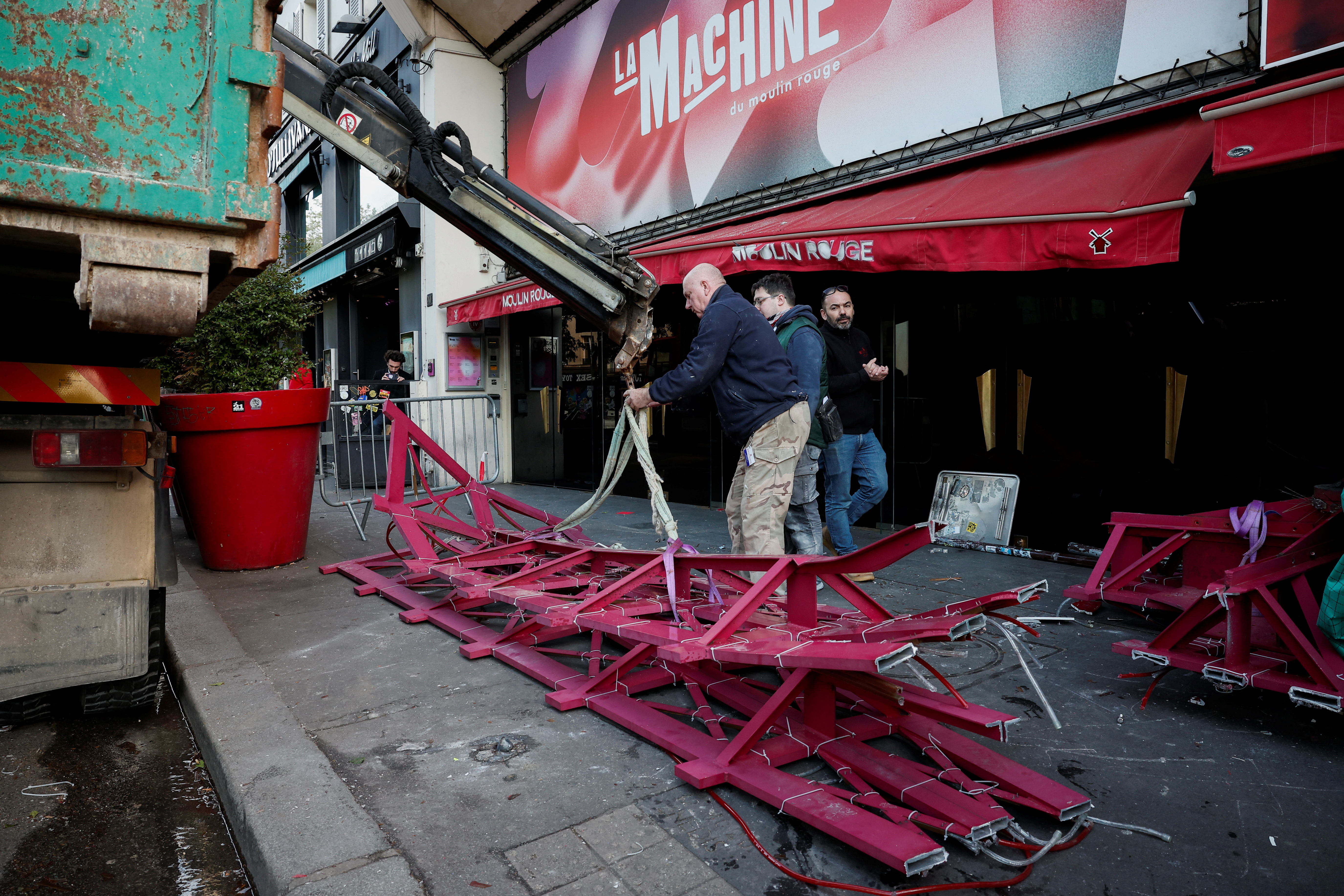 The broken sails of the landmark red windmill atop the Moulin Rouge, Paris' most famous cabaret club, are taken away after they fell off during the night in Paris
