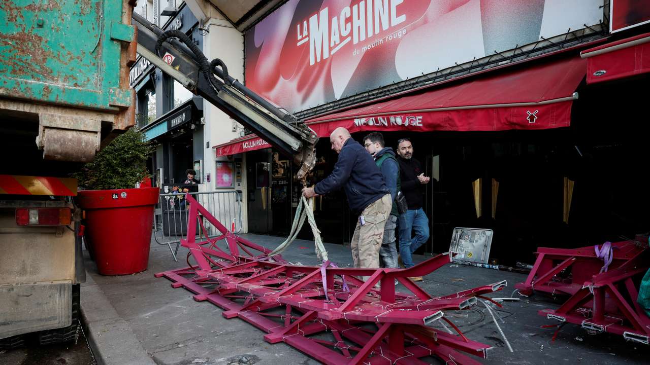 The broken sails of the landmark red windmill atop the Moulin Rouge, Paris' most famous cabaret club, are taken away after they fell off during the night in Paris