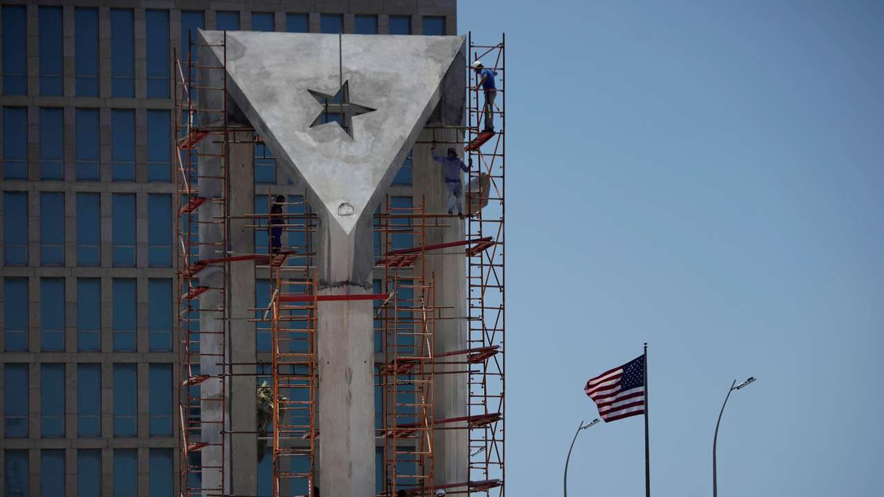 Men work in a monument in front of the U.S. Embassy in Havana