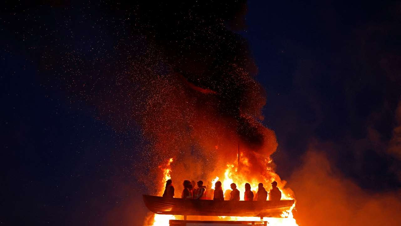 Bonfire burns with effigy of migrants in a boat atop it, in Moygashel
