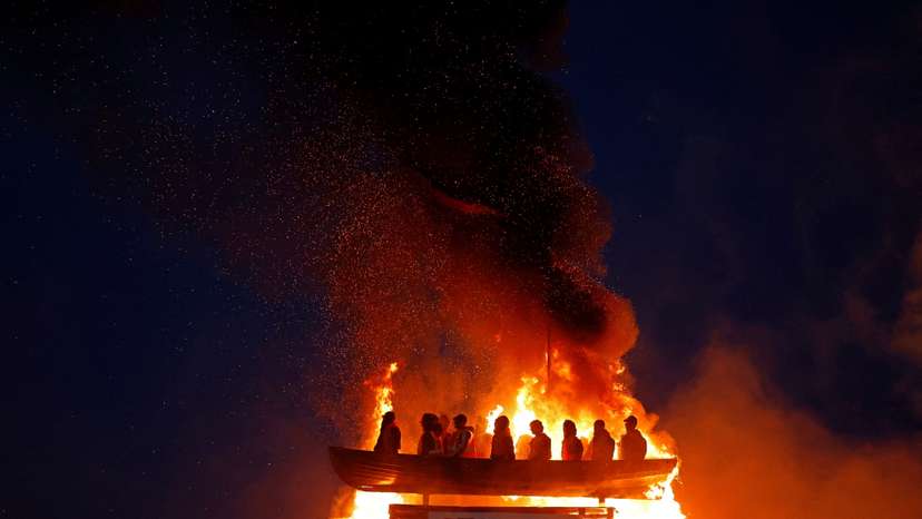 Bonfire burns with effigy of migrants in a boat atop it, in Moygashel