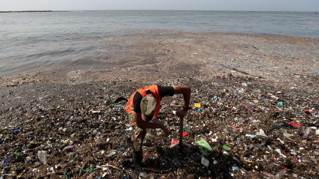 A soldier pauses while cleaning plastic and other debris on the shores of Montesinos beach, in Santo Domingo
