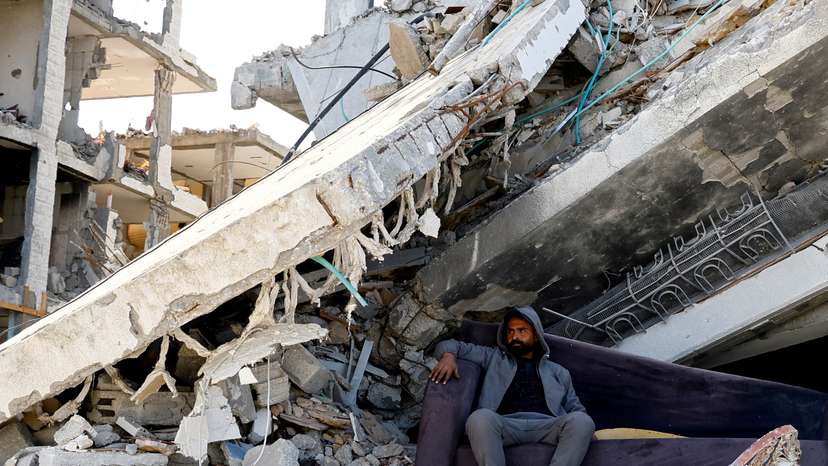 FILE PHOTO: A Palestinian man sits amidst the rubble of buildings destroyed during the Israeli offensive, amid a ceasefire between Israel and Hamas, in Rafah