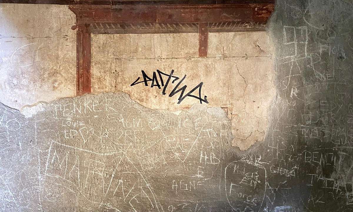 A sign made with a black marker by a tourist is pictured on the wall of a domus of the Herculaneum Archaeological Park, in Ercolano, Naples