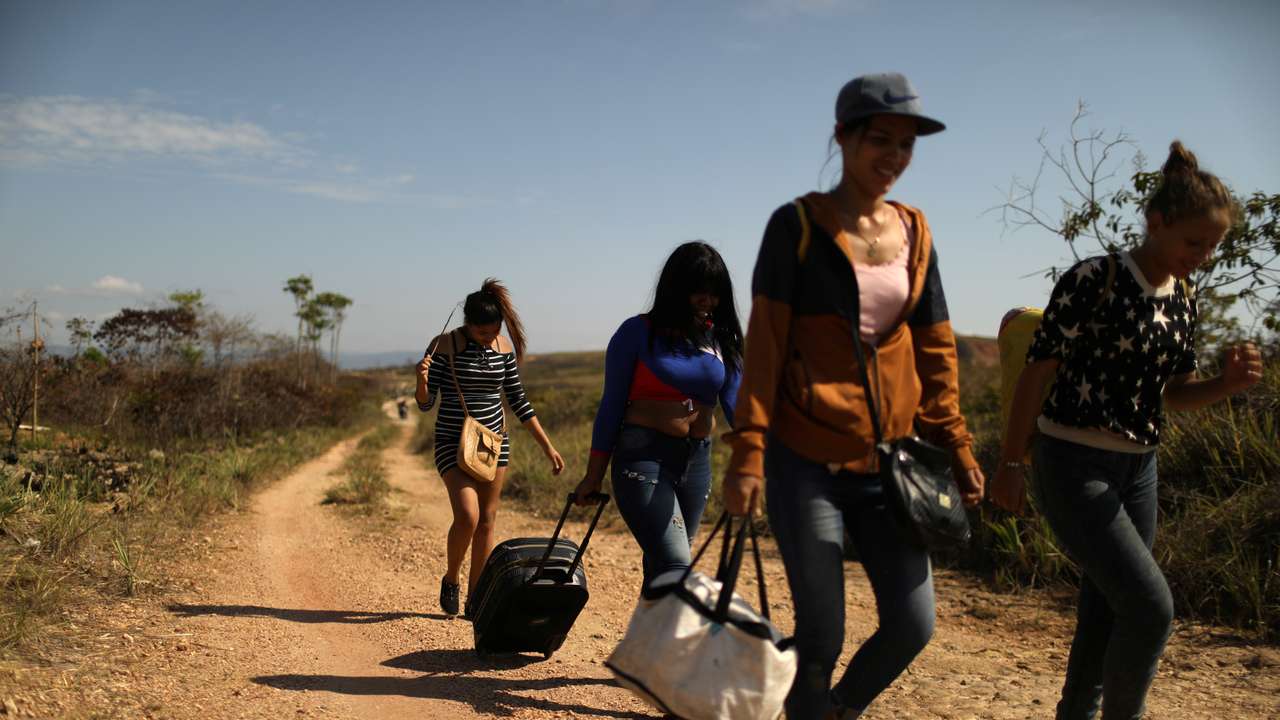 Venezuelan migrants walk along a trail into Brazil in the border city of Pacaraima