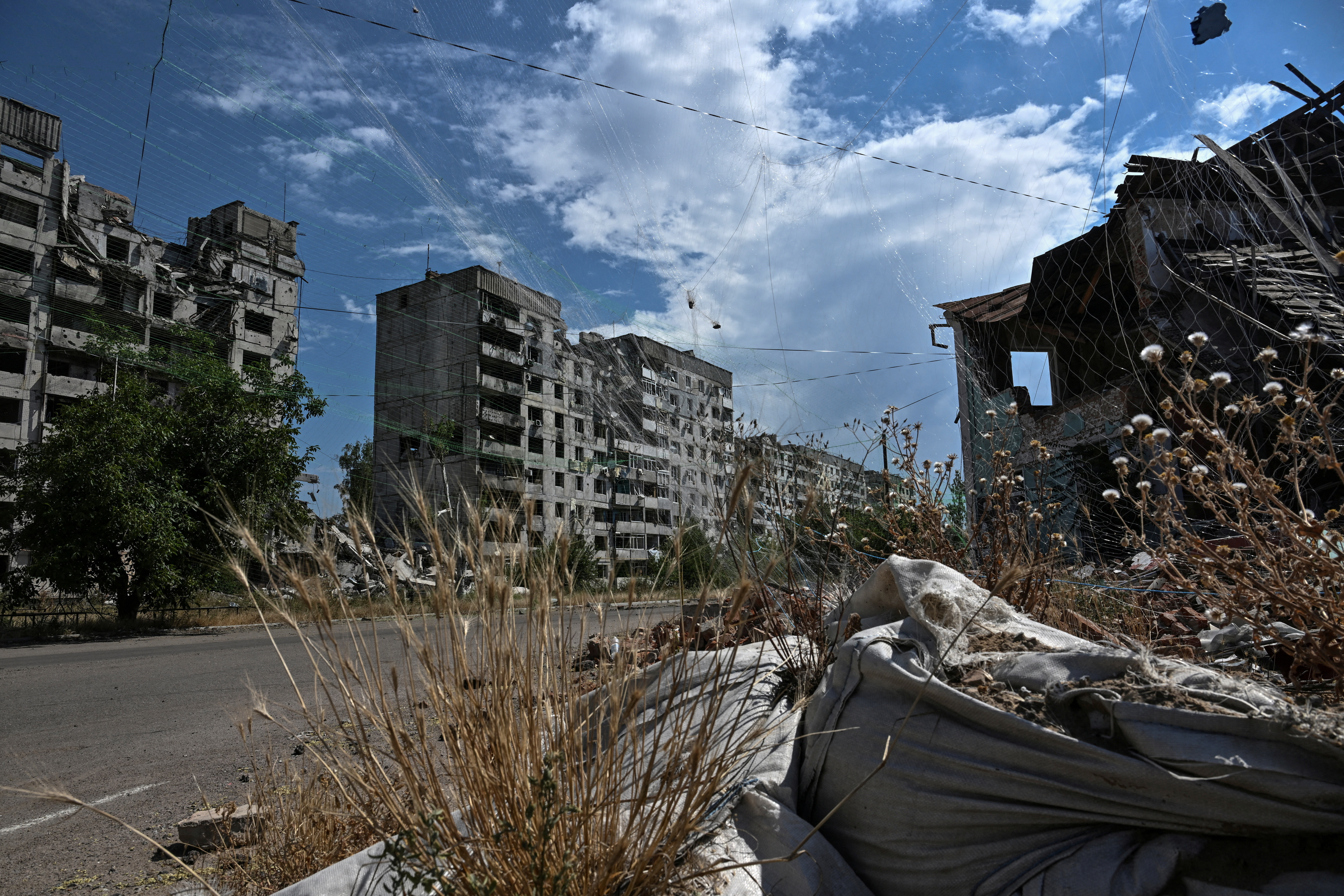 FILE PHOTO: View shows residential building damaged by Russian military strikes and anti-drone nets installed over a street in the frontline town Orikhiv