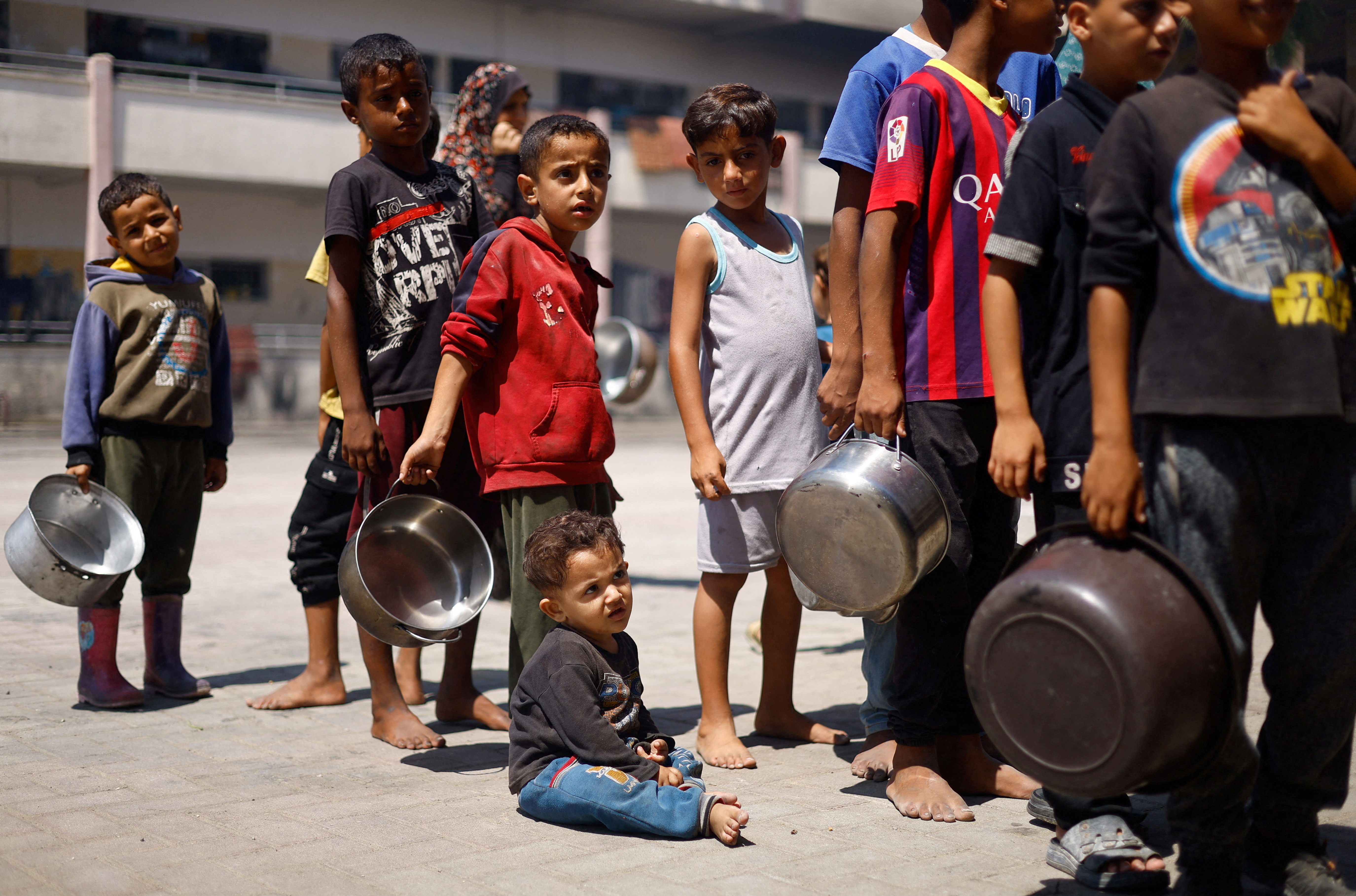 Palestinians gather to receive food cooked by a charity kitchen, amid food scarcity, as Israel-Hamas conflict continues, in Khan Younis in the southern Gaza Strip