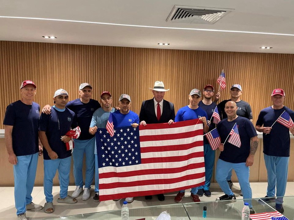 U.S. citizens released from Venezuela pose for a photo holding U.S. flags after a prisoner swap