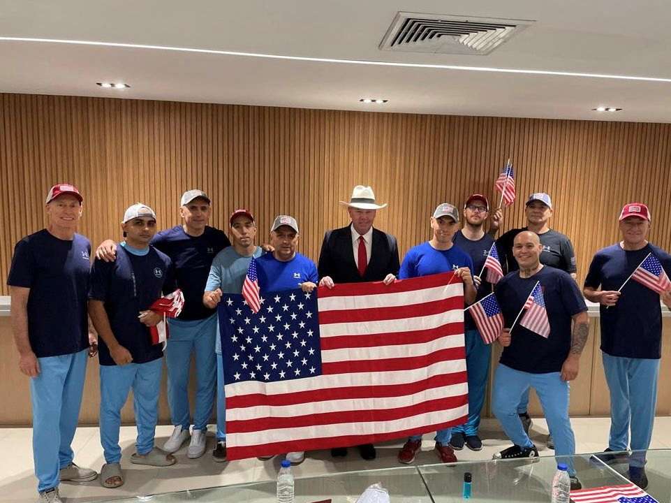 U.S. citizens released from Venezuela pose for a photo holding U.S. flags after a prisoner swap
