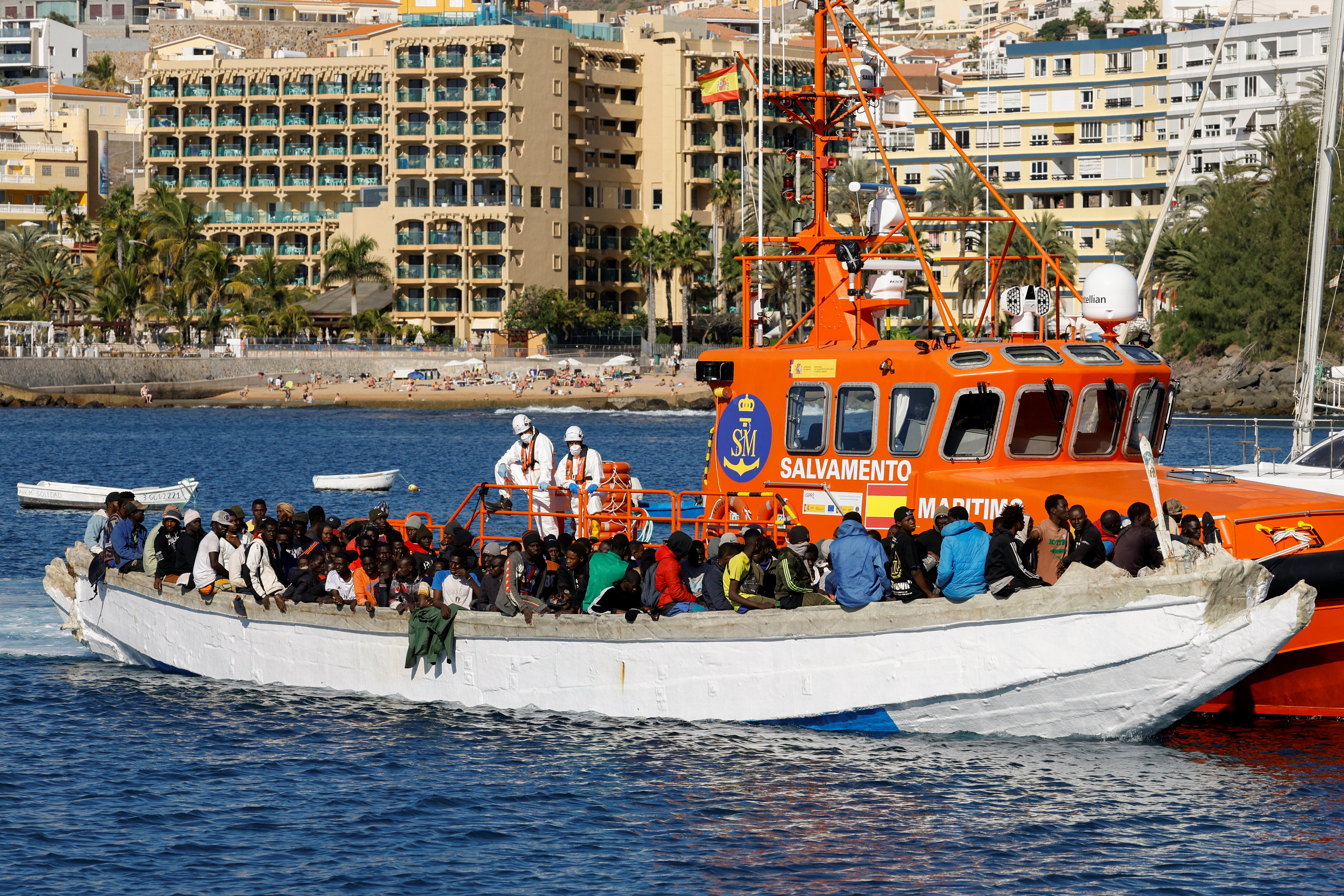 A group of migrants wait to disembark from a wooden boat after being rescued by a Spanish coast guard vessel in the port of Arguineguin