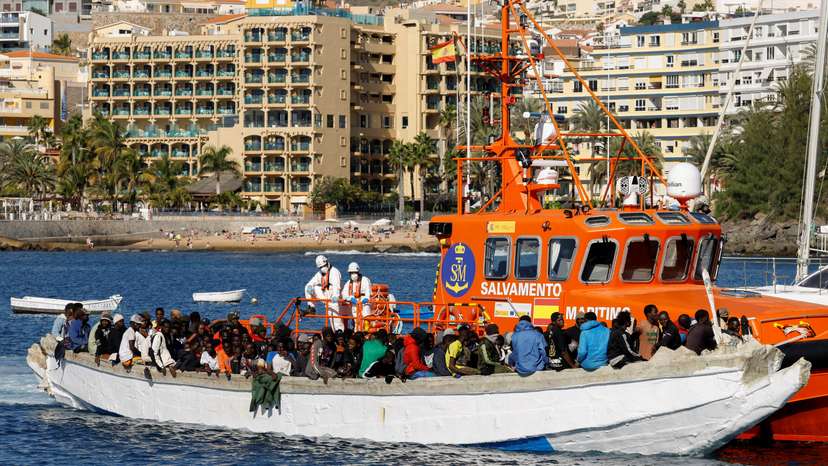 A group of migrants wait to disembark from a wooden boat after being rescued by a Spanish coast guard vessel in the port of Arguineguin
