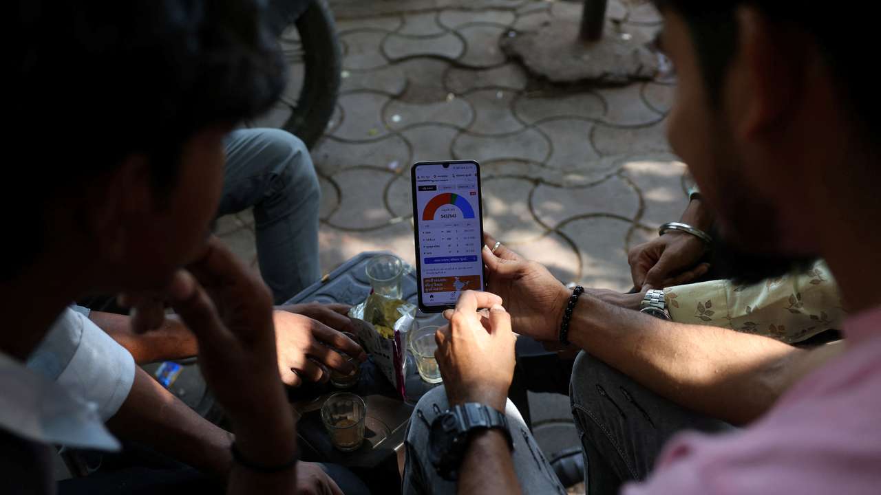 People watch election results on a mobile phone at a roadside tea stall in Ahmedabad
