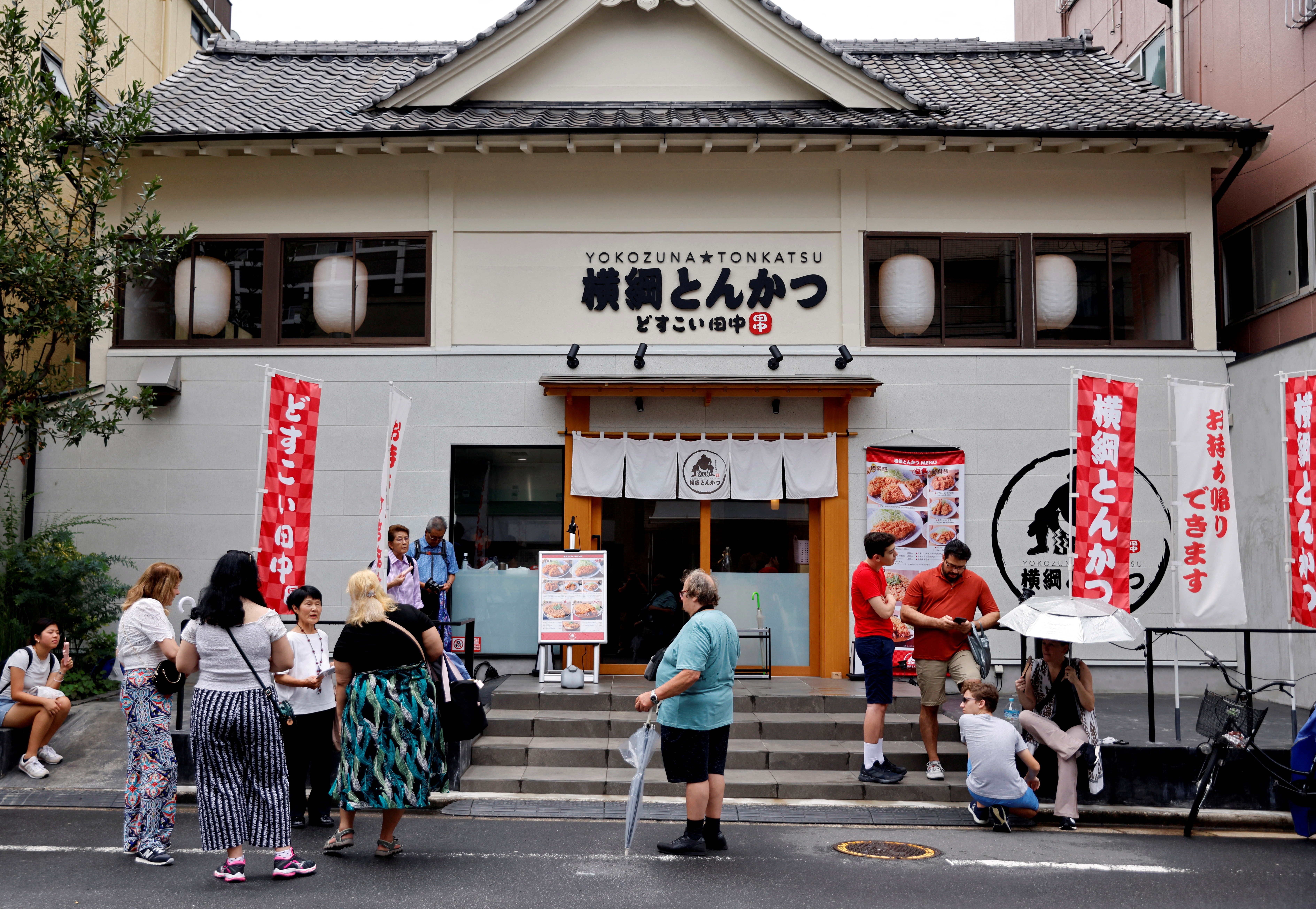 FILE PHOTO: Tourists from abroad wait for Yokozuna Tonkatsu Dosukoi Tanaka, a sumo wrestling themed restaurant to open, in Tokyo