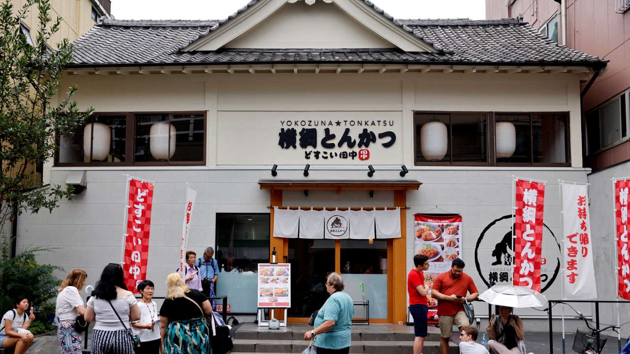 FILE PHOTO: Tourists from abroad wait for Yokozuna Tonkatsu Dosukoi Tanaka, a sumo wrestling themed restaurant to open, in Tokyo