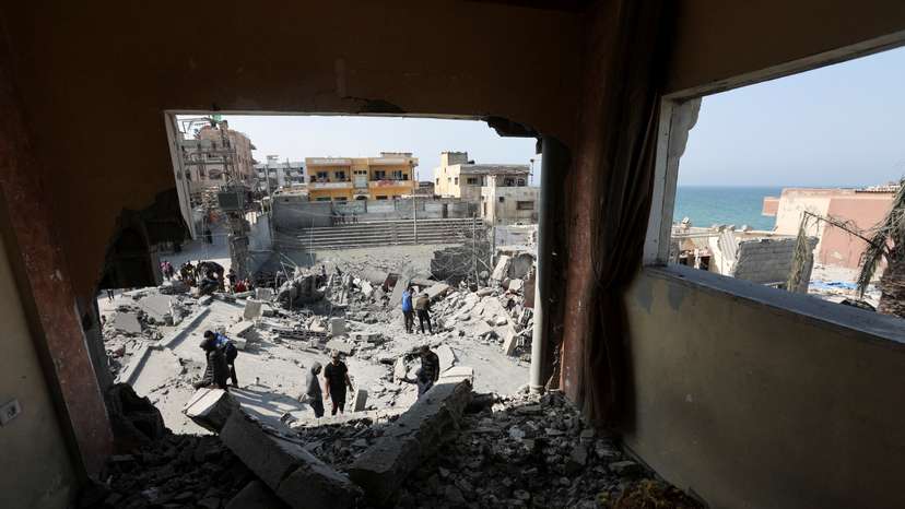 Palestinians inspect the site of an Israeli strike on a residential building, in Deir Al-Balah
