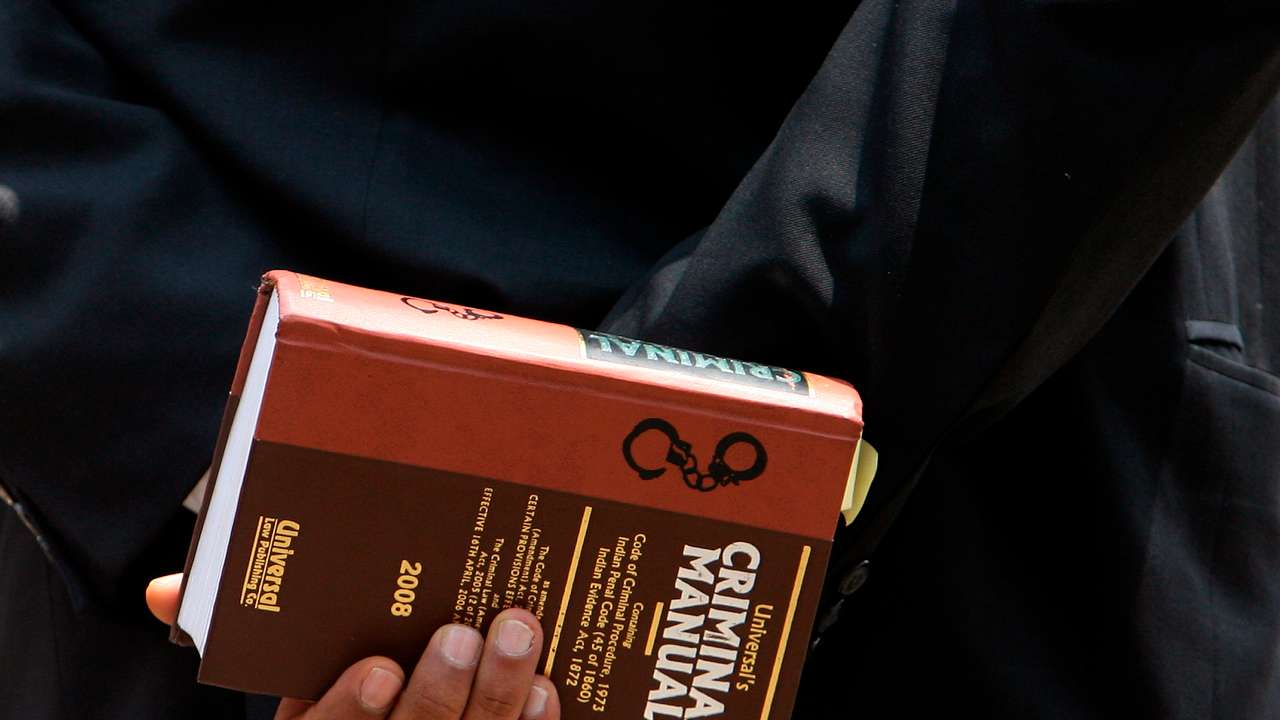 Lawyer holds a book as he waits to enter the Arthur Road jail in Mumbai