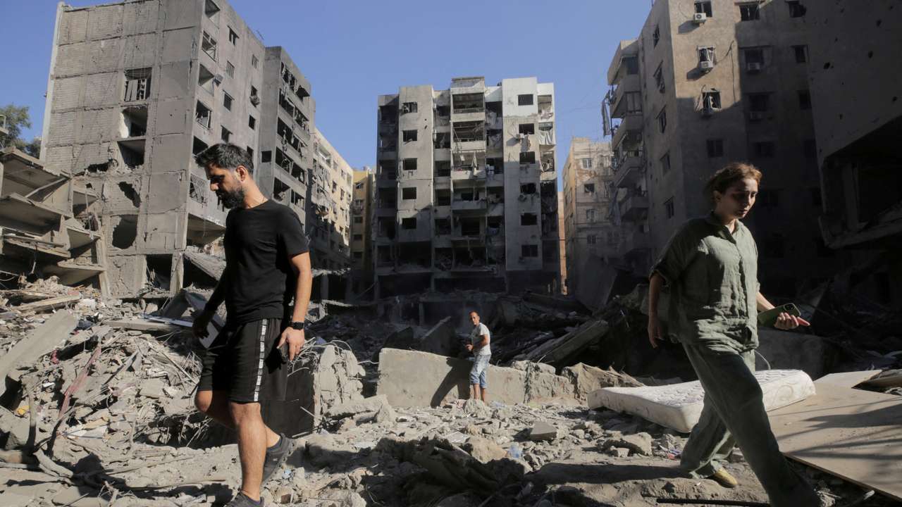 People walk on the rubble at the site of the Israeli airstrike that killed Lebanon's Hezbollah leader Sayyed Hassan Nasrallah on Friday, in Beirut's southern suburbs