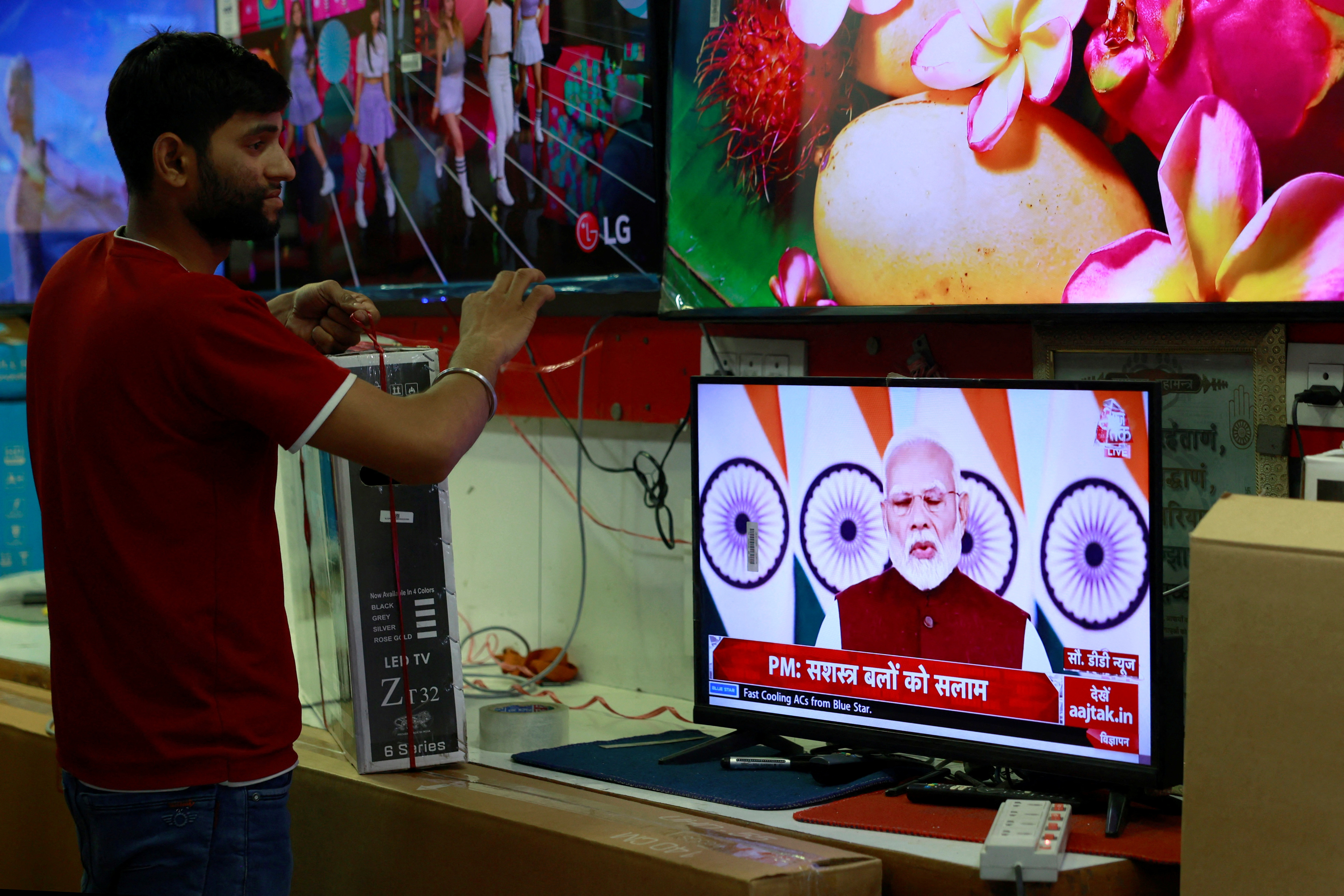 A salesman watches Prime Minister Narendra Modi addressing the nation on a TV screen inside a shop in the old quarters of Delhi
