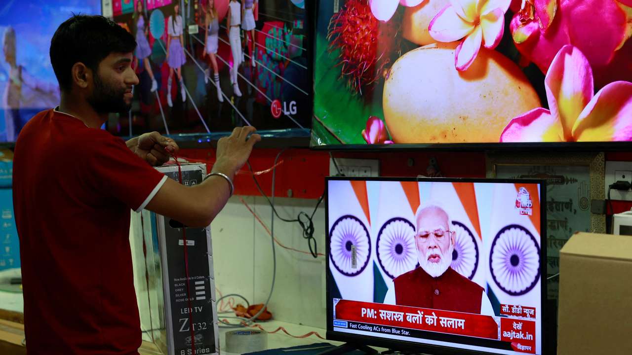A salesman watches Prime Minister Narendra Modi addressing the nation on a TV screen inside a shop in the old quarters of Delhi