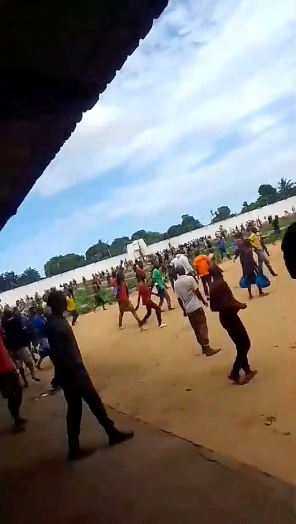 A large group of people gather within the prison during a riot, in Maputo