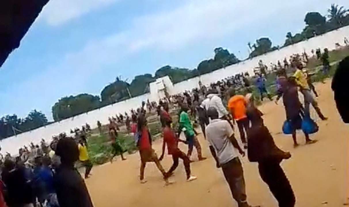 A large group of people gather within the prison during a riot, in Maputo