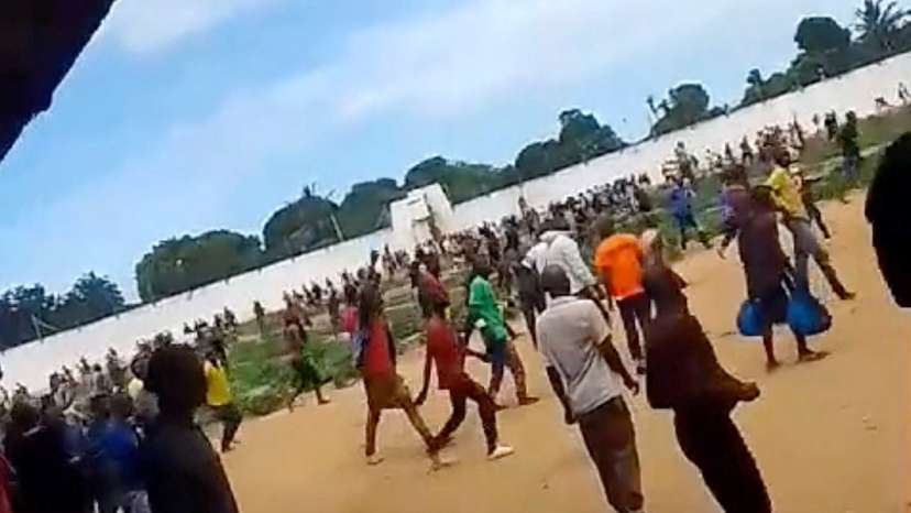 A large group of people gather within the prison during a riot, in Maputo