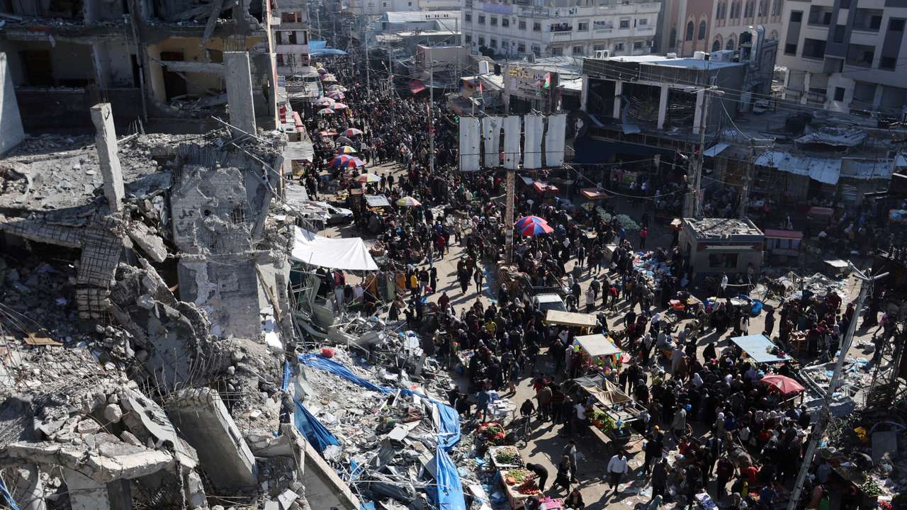 Palestinians shop near the ruins of houses and buildings destroyed in Israeli strikes during the conflict